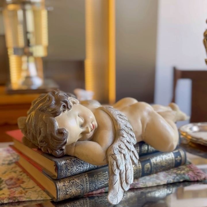 Figura de un ángel de yeso sobre una repisa.