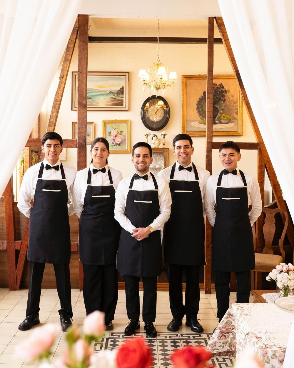 El equipo de Café Cupido con delantales, bajo la escalera de madera del salón.