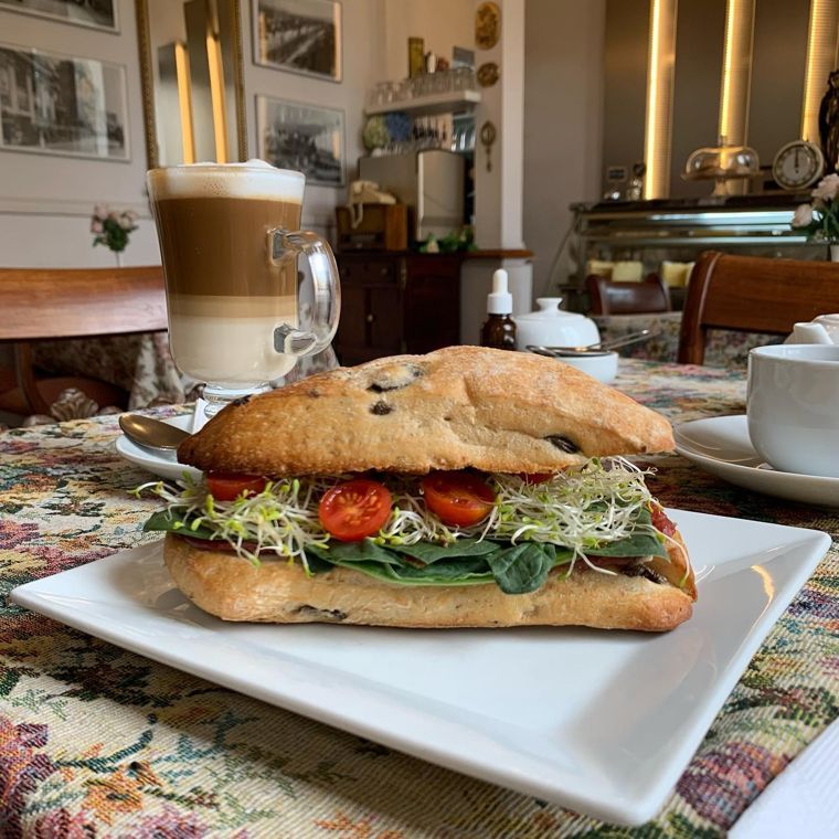 Sándwich de ciabatta con verduras servido en plato blanco.